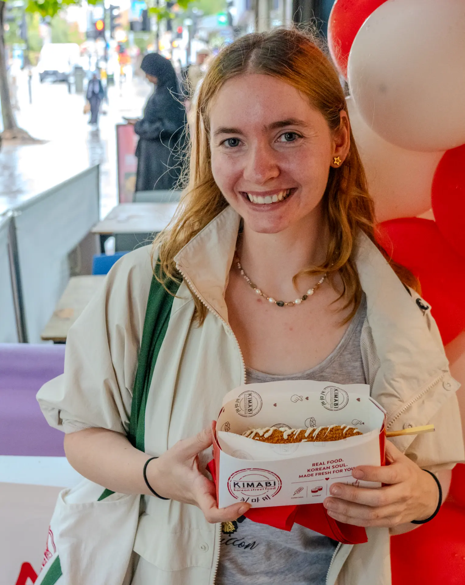 Guest holding an open Kimabi box with a freshly made corn dog