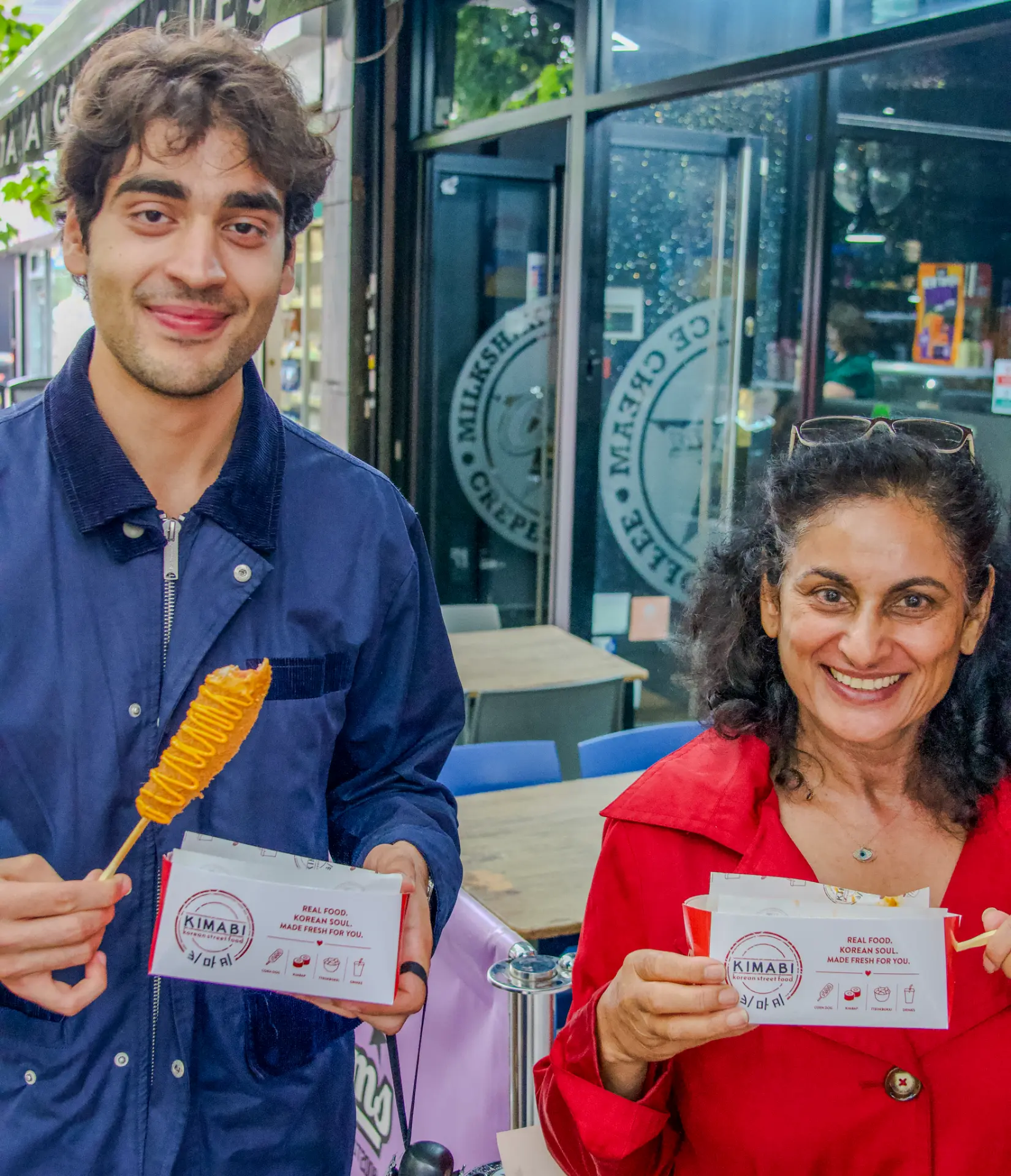 Two guests smiling outside Kimabi holding a corn dog and Kimabi boxes
