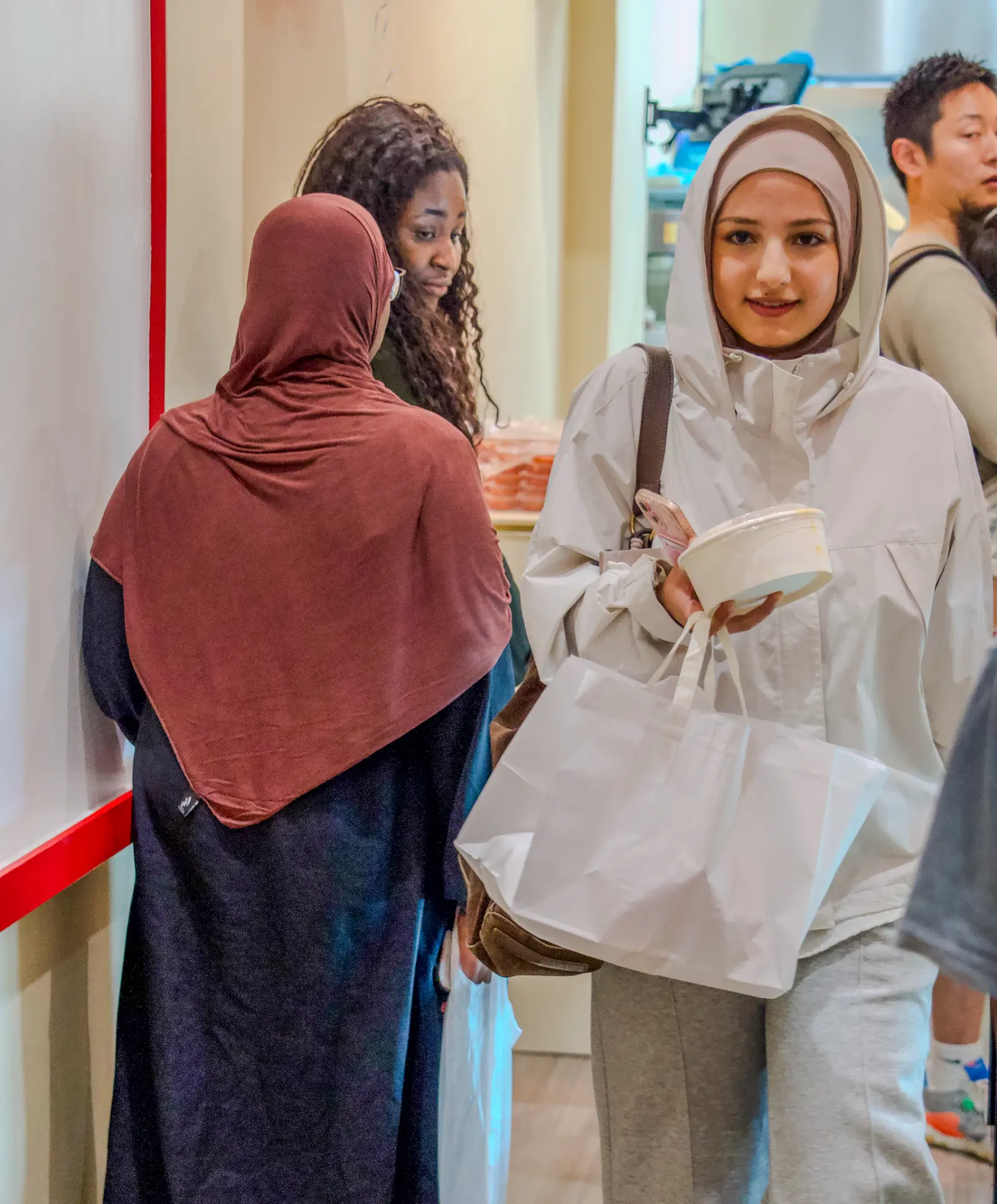 Guests holding Kimabi takeaway bags and a tteokbokki cup